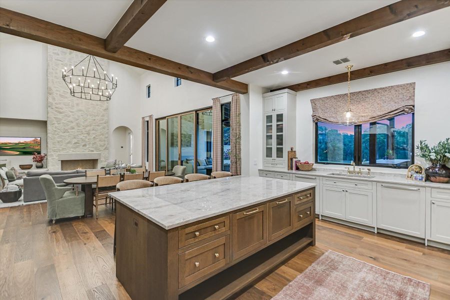 Kitchen with white cabinetry, pendant lighting, a chandelier, open floor plan, and a high ceiling Kitchen with white cabinetry, pendant lighting, a chandelier, open floor plan, and a high ceiling