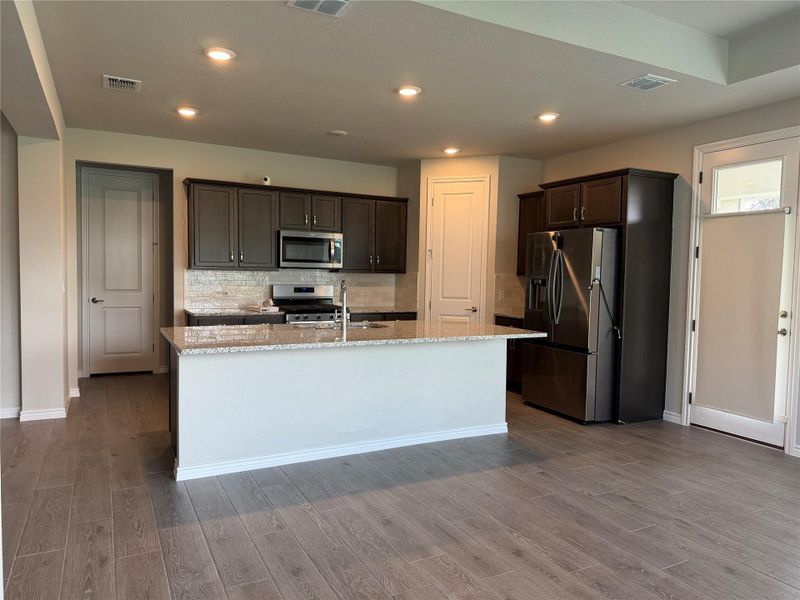 A well-appointed kitchen features rich cabinetry, stainless steel appliances, and a central island.