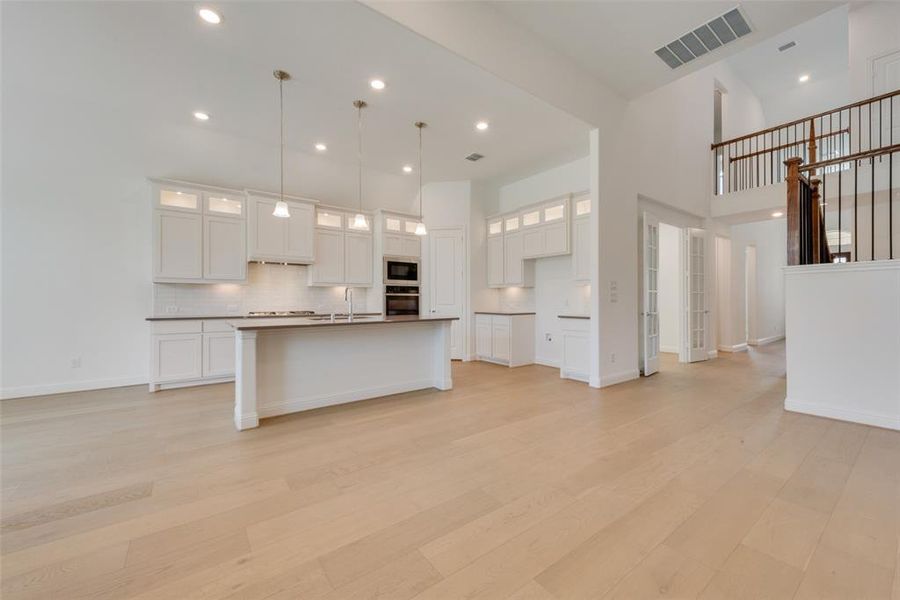 Kitchen featuring light hardwood / wood-style floors, white cabinetry, and an island with sink