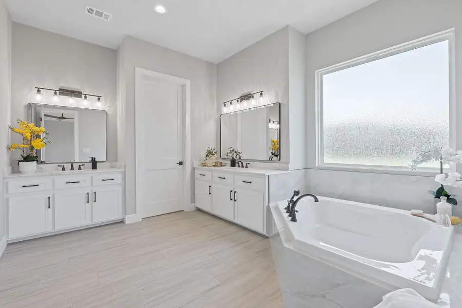 Full bath featuring two vanities and a garden tub