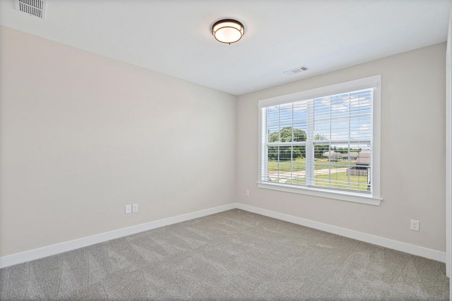Spacious room featuring neutral paint, gray carpet, a white framed window with blinds, and a flush mount ceiling light Spacious room featuring neutral paint, gray carpet, a white framed window with blinds, and a flush mount ceiling light