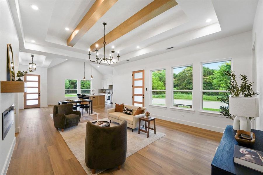 Spacious living area featuring high ceilings with exposed wood beams, recessed lighting, and a contemporary chandelier