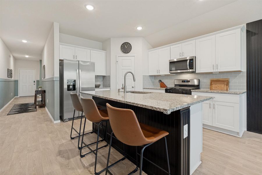 A well-appointed kitchen showcasing a spacious island with granite counters and contemporary stainless steel appliances.