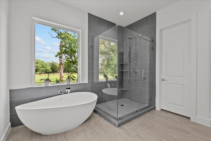 Massive freestanding tub with natural views and a well equipped glass enclosed spacious walk-in shower.
