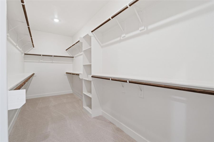 Primary walk-in closet with built-in shelving and double hanging rods on multiple walls, so your wardrobe actually has a place to live. Primary walk-in closet with built-in shelving and double hanging rods on multiple walls, so your wardrobe actually has a place to live.