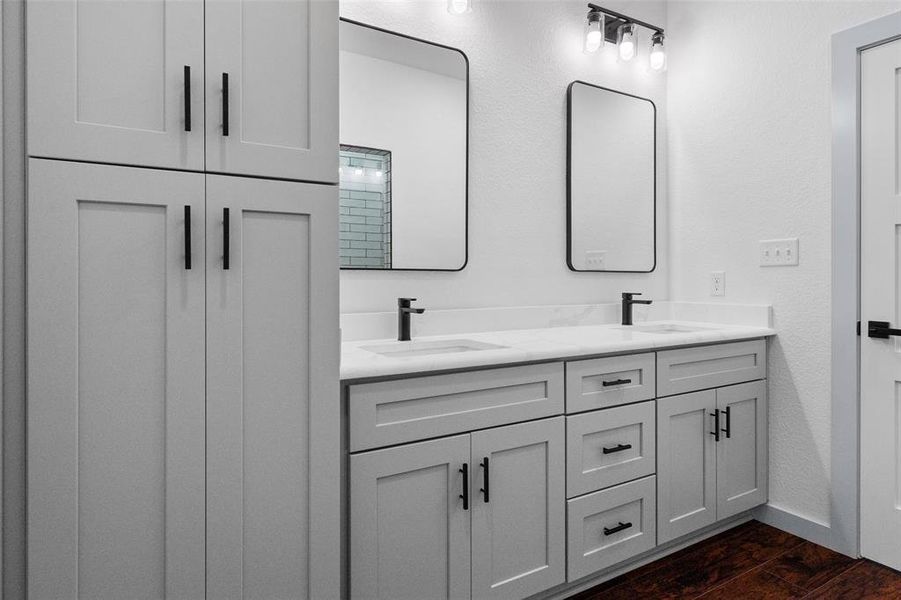 Bathroom featuring double vanity and dark wood finished floors