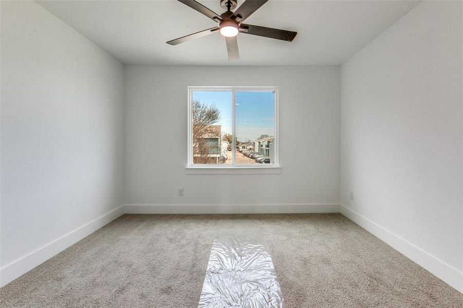 Empty room with light colored carpet and a ceiling fan