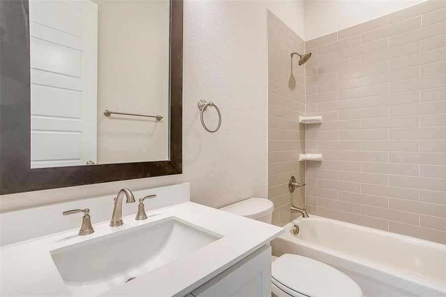 Full bathroom featuring tiled shower / bath combo, toilet, and vanity