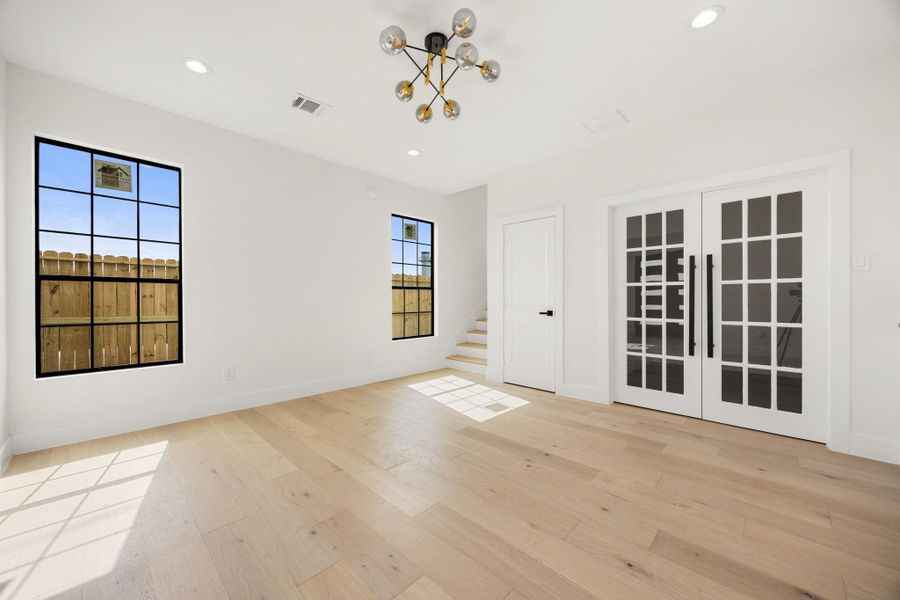 From the opposite perspective, this view highlights the spacious living area, two windows bringing in natural light, the home office, and the staircase leading to the second level.