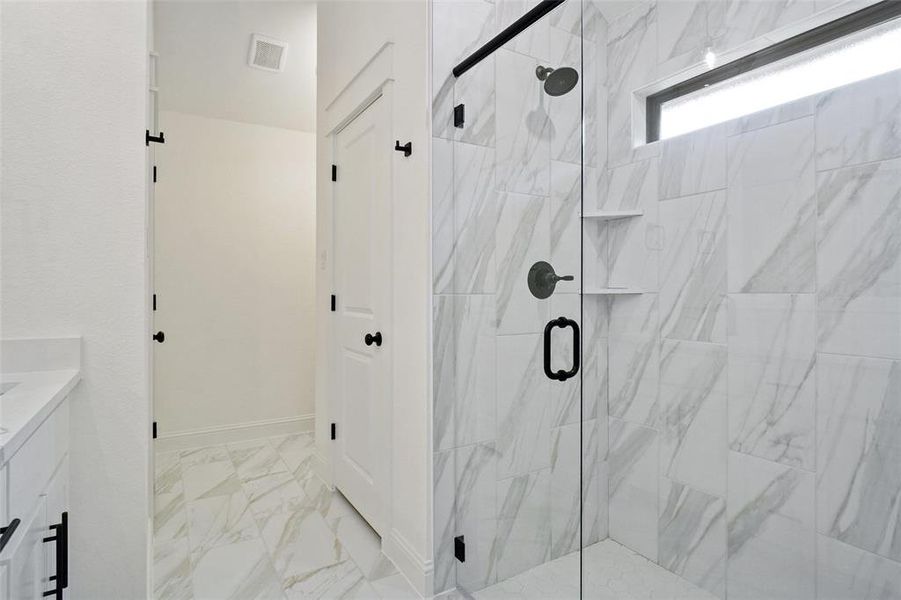 Bathroom with vanity, a marble finish shower, and light marble finish floors