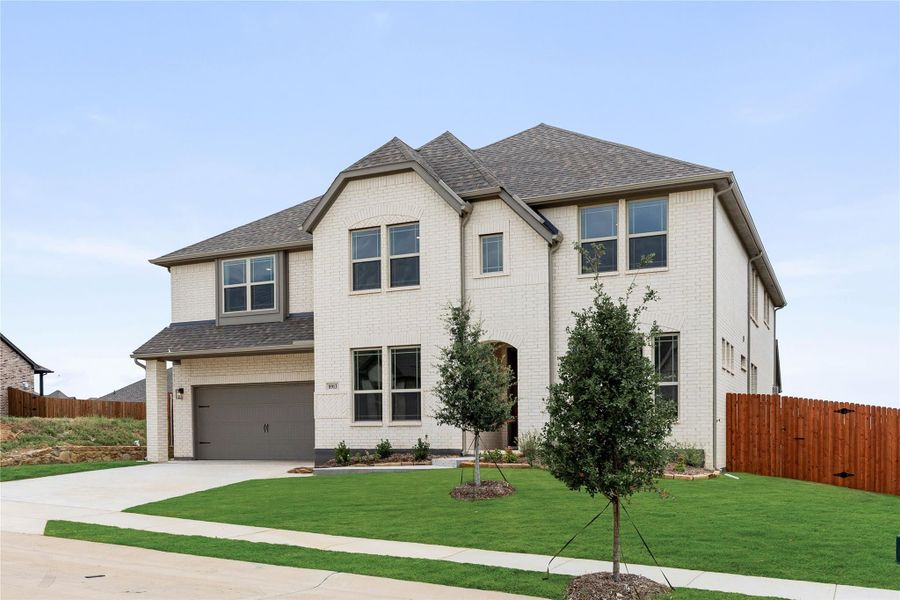 Two-story brick home with two-car garage, arched entry, and manicured front lawn