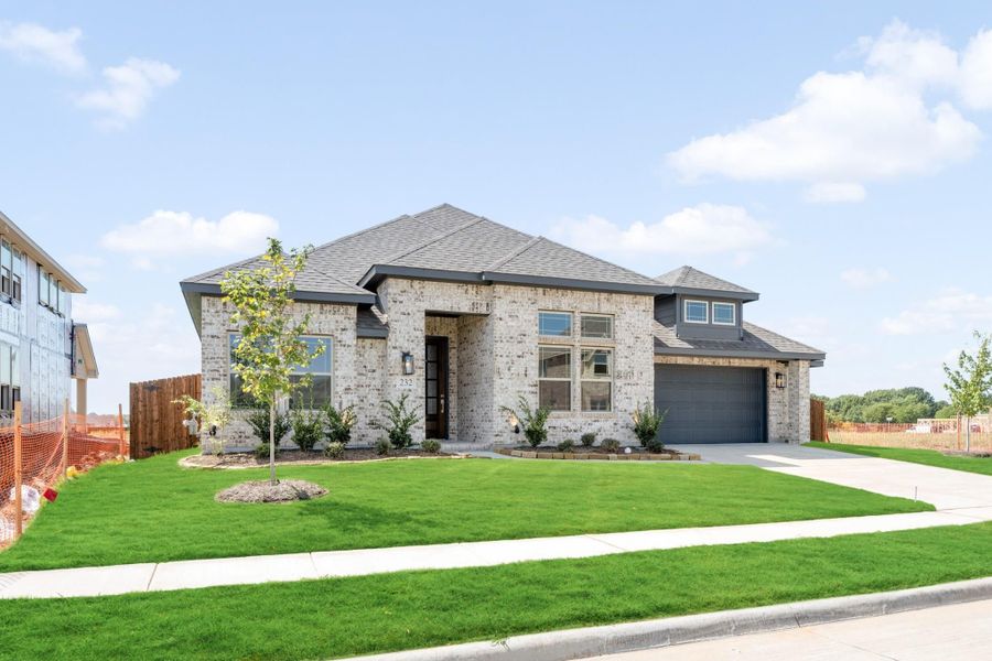 Single-story home with light brick exterior, gray roof, two-car garage, and manicured front lawn.