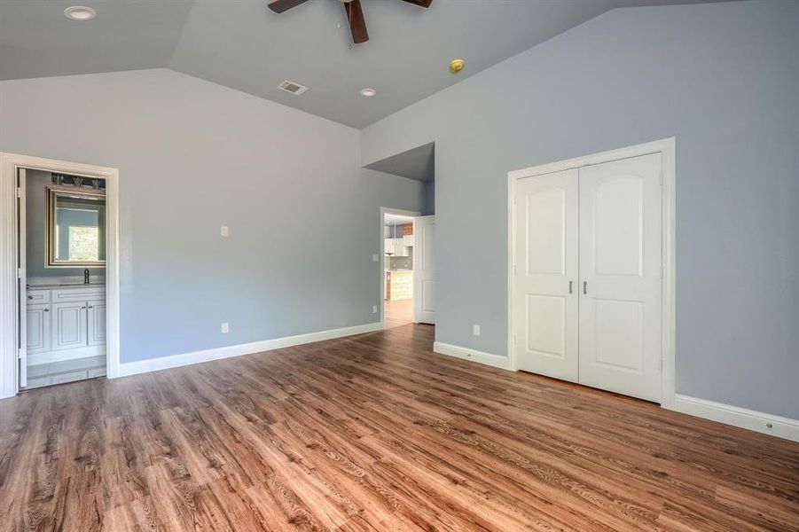 Unfurnished bedroom featuring ensuite bathroom, wood-type flooring, a closet, and ceiling fan