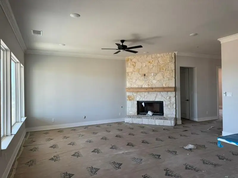 Unfurnished living room with ornamental molding, a fireplace, and a ceiling fan