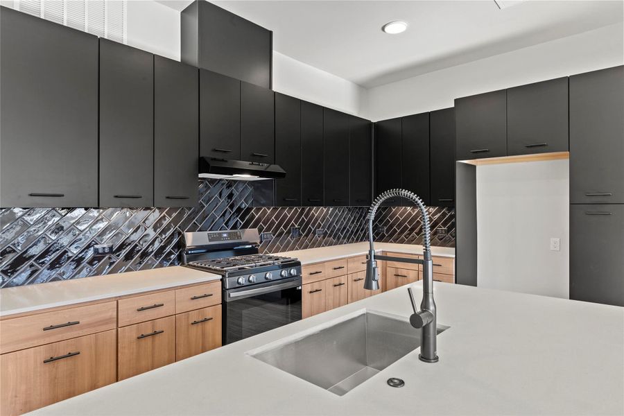 Kitchen featuring stainless steel range with gas cooktop, sink, light brown cabinets, and decorative backsplash