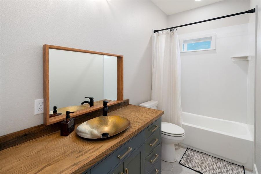 Full bathroom featuring tile patterned floors, vanity, toilet, and shower / bath combo with shower curtain