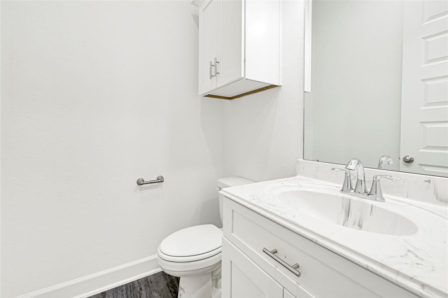 This bathroom features a modern design with white cabinetry, a sleek marble countertop, and a large mirror. It includes a toilet and a silver faucet, providing a clean and bright space. This bathroom features a modern design with white cabinetry, a sleek marble countertop, and a large mirror. It includes a toilet and a silver faucet, providing a clean and bright space.
