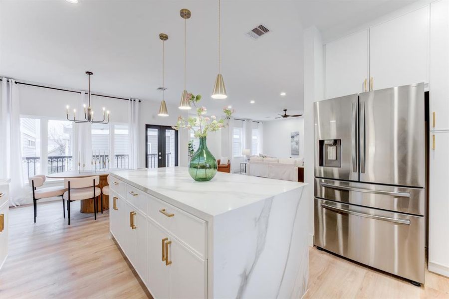 The stainless steel refrigerator stays with the home. The quartz island has functioning doors and cabinets for optimal storage.