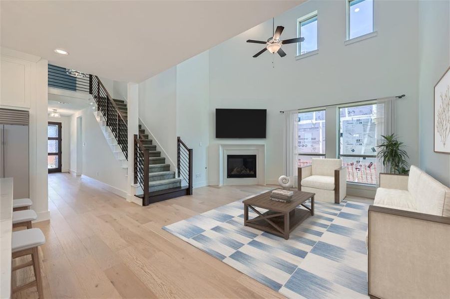 Virtually Staged Photo - Living room with plenty of natural light, a high ceiling, light hardwood / wood-style flooring, and ceiling fan