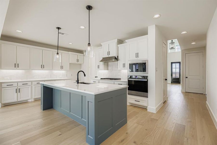 Kitchen featuring white cabinetry, appliances with stainless steel finishes, a kitchen island with sink, pendant lighting, and recessed lighting