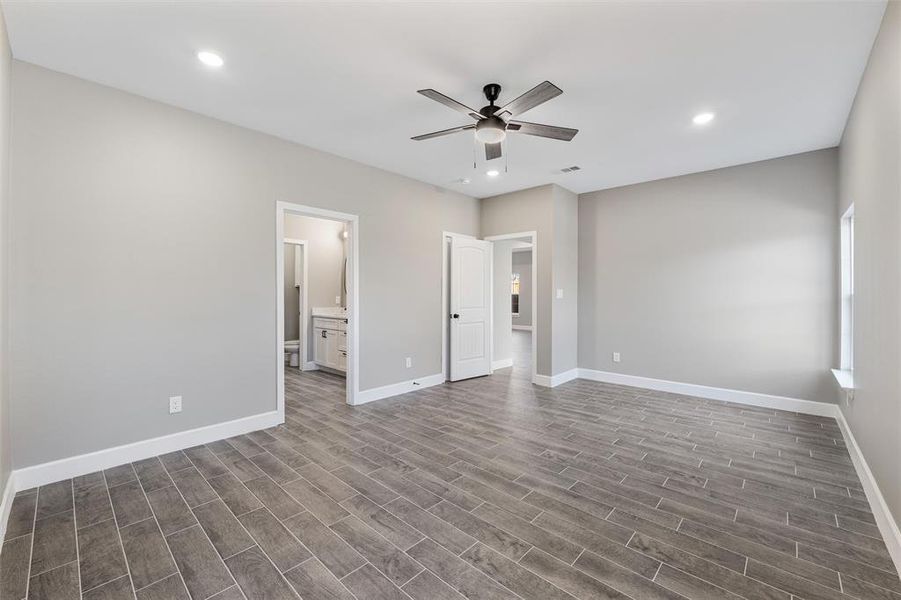 Unfurnished bedroom featuring ensuite bathroom, dark hardwood / wood-style floors, and ceiling fan