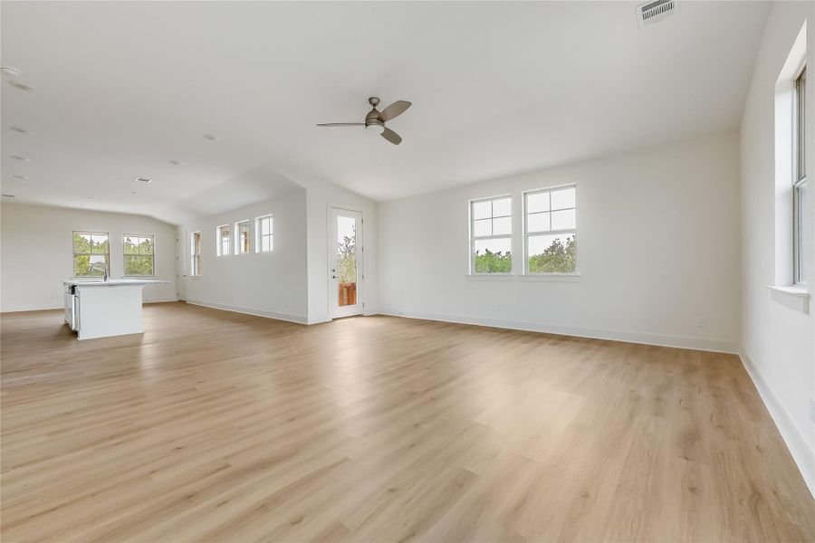 Unfurnished living room with light wood-type flooring, ceiling fan, and lofted ceiling