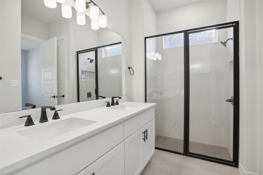 Bathroom with double vanity, a stall shower, a sink, and tile patterned floors