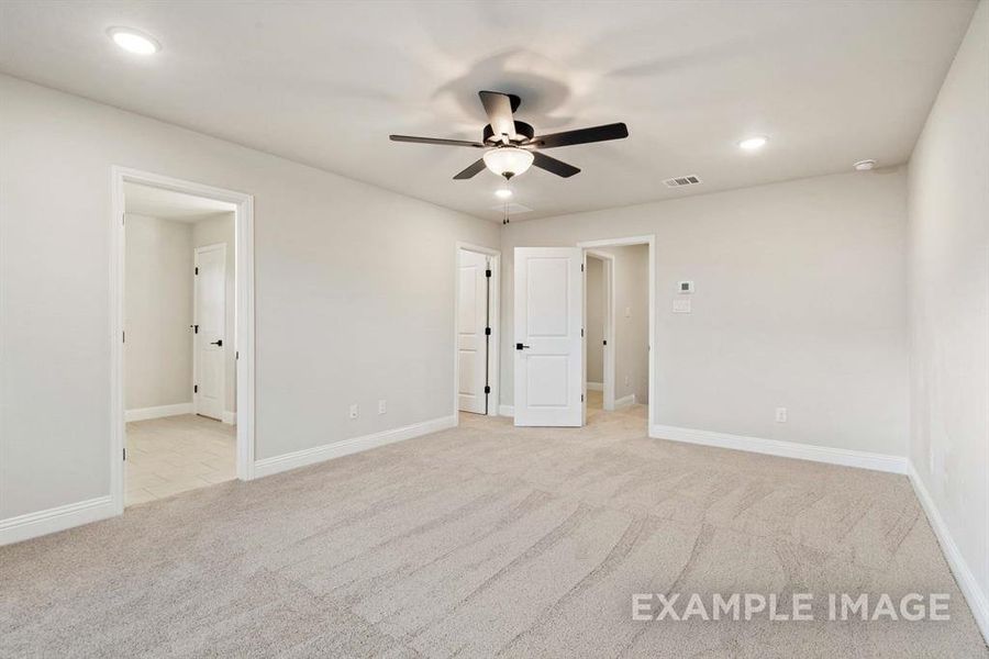 Unfurnished bedroom with light colored carpet, ensuite bath, and ceiling fan