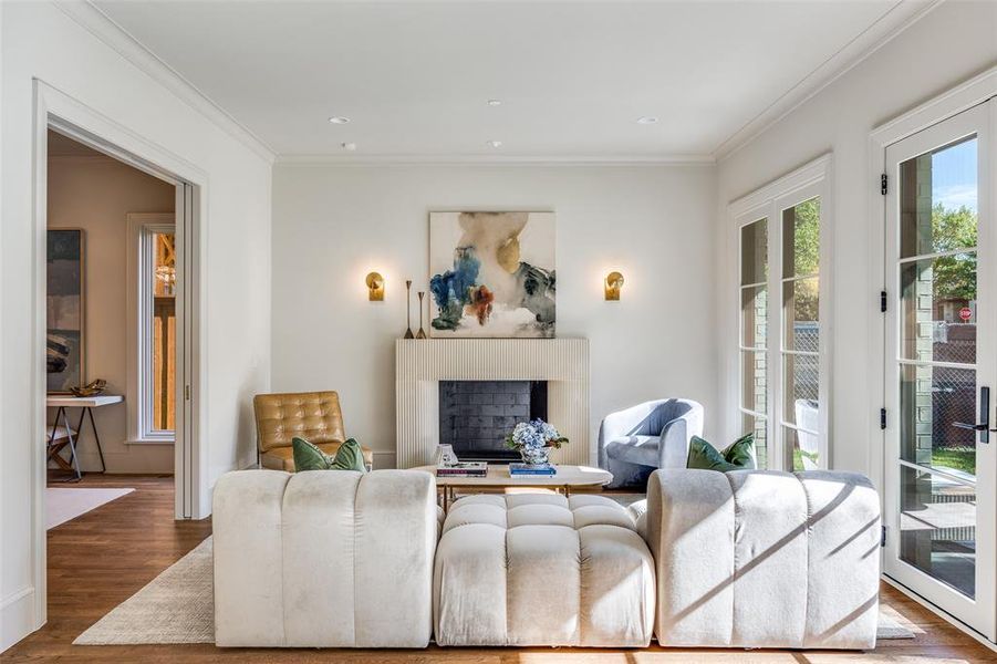 Living area featuring a fireplace, wood finished floors, ornamental molding, and recessed lighting Living area featuring a fireplace, wood finished floors, ornamental molding, and recessed lighting
