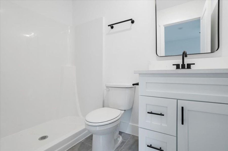 Bathroom featuring vanity, toilet, a shower, and tile patterned flooring