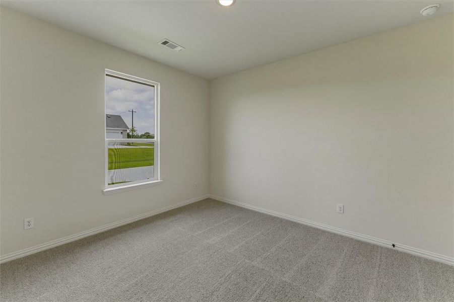 Spacious room with light neutral wall paint, gray carpet flooring, white trim, and a prominent window Spacious room with light neutral wall paint, gray carpet flooring, white trim, and a prominent window