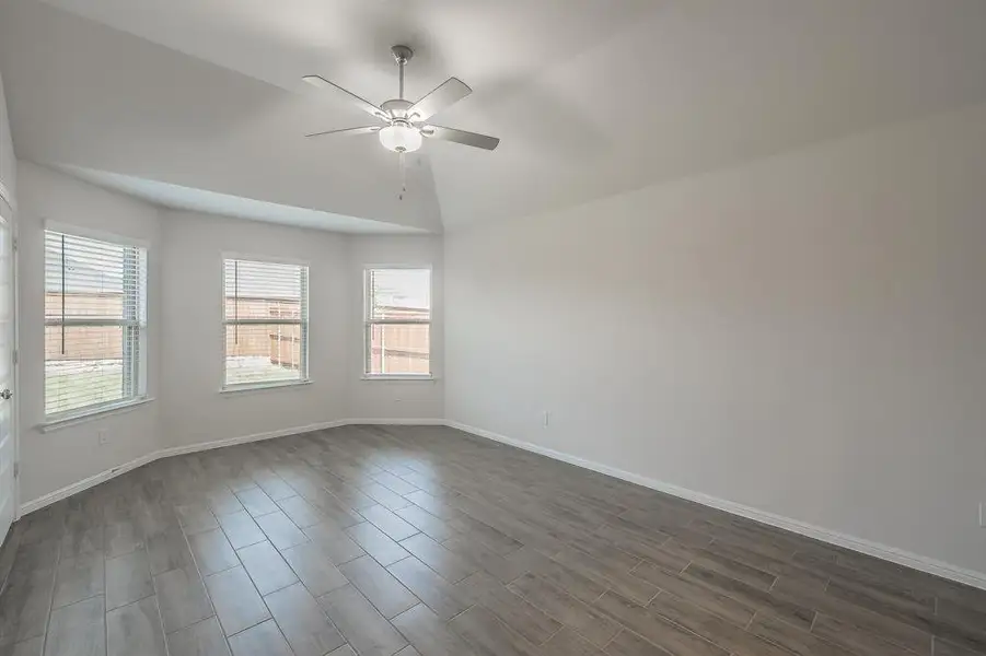 Empty room with wood tiled floors, ceiling fan, and lofted ceiling Empty room with wood tiled floors, ceiling fan, and lofted ceiling