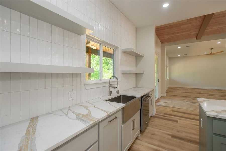 Kitchen with light wood-type flooring, backsplash, beam ceiling, and wooden ceiling