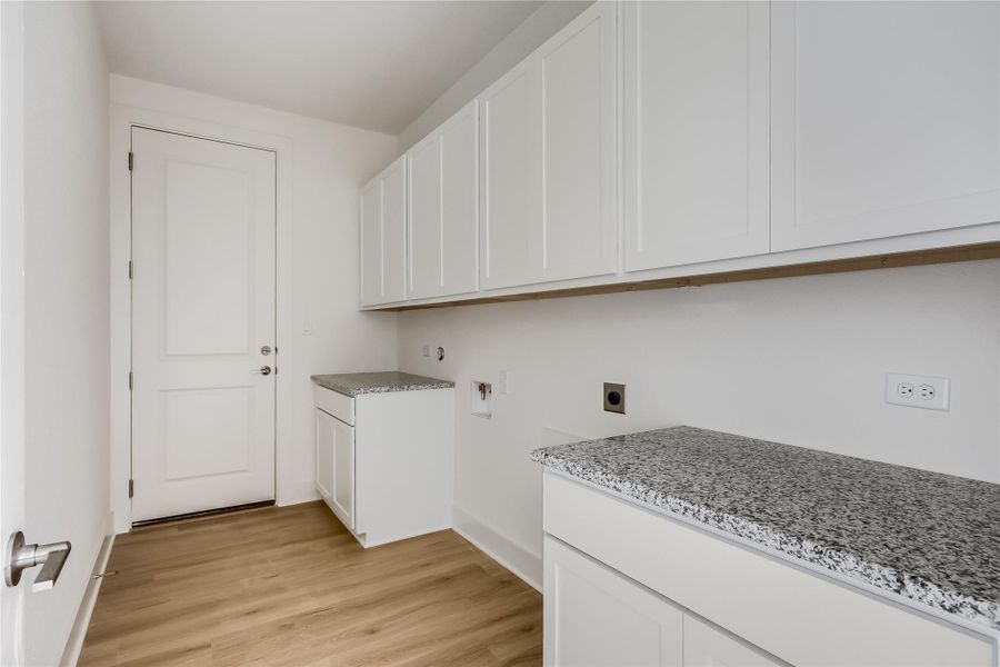 Laundry area with electric dryer hookup, washer hookup, cabinet space, and light wood finished floors