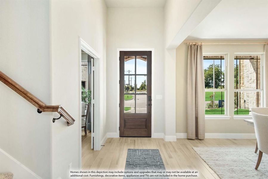 Bright home entryway with dark wood glass-panel front door, light hardwood floors, and staircase with wood railing Bright home entryway with dark wood glass-panel front door, light hardwood floors, and staircase with wood railing