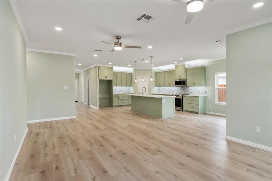 Kitchen featuring a center island, ceiling fan, light hardwood / wood-style floors, green cabinetry, and appliances with stainless steel finishes