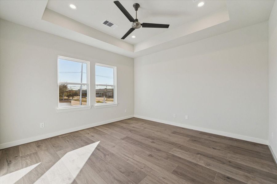 The spacious primary suite features large windows and elevated ceilings, creating a peaceful retreat filled with natural light.