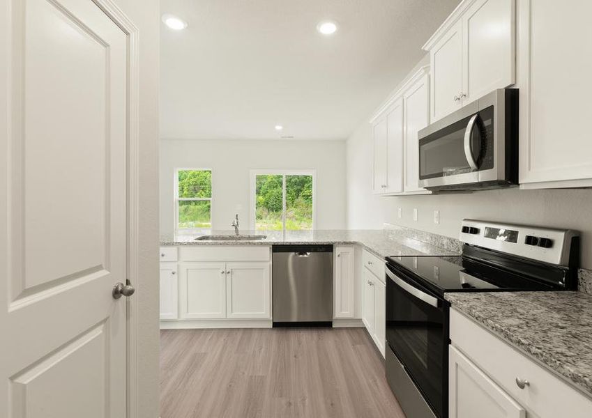 The kitchen has white wood cabinetry