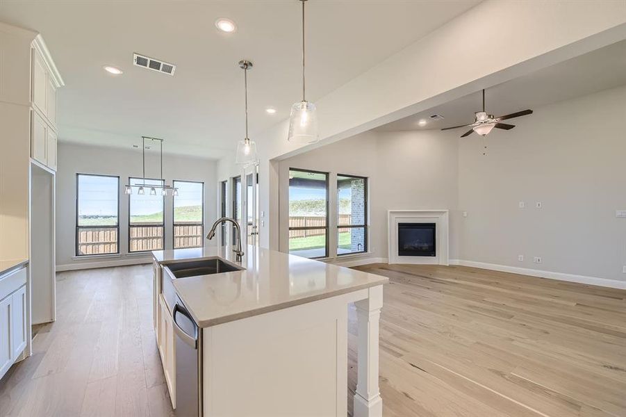 Kitchen featuring white cabinets, ceiling fan with notable chandelier, sink, and a healthy amount of sunlight