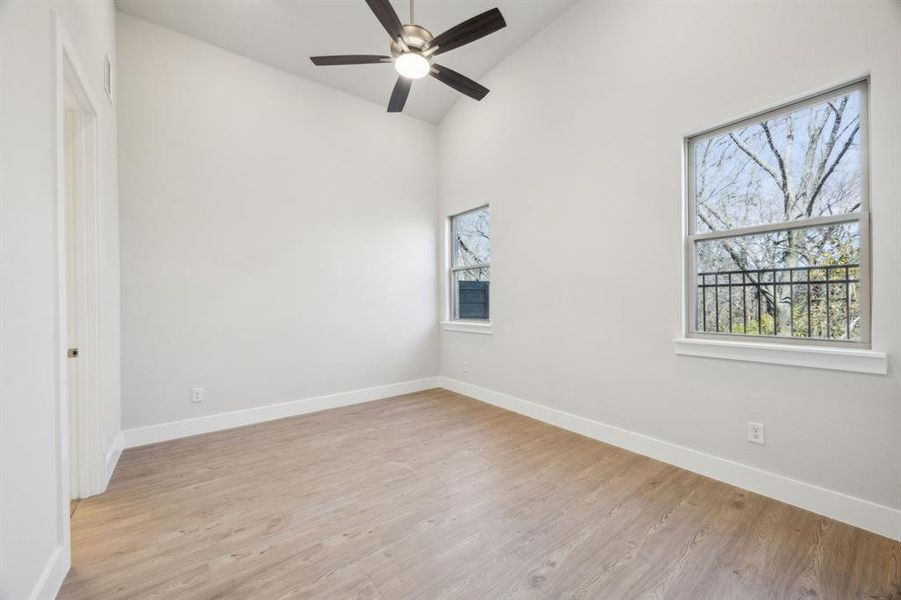 Primary bedroom with vaulted ceiling, a wealth of natural light, ceiling fan, and light hardwood / wood-style flooring