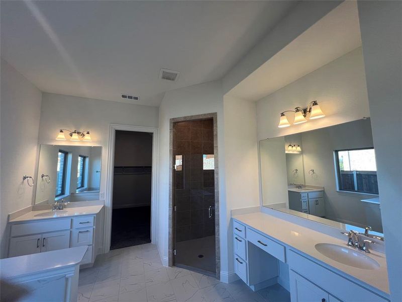 Bathroom with marble finish floor, visible vents,  separate his & hers vanity, and a stall shower