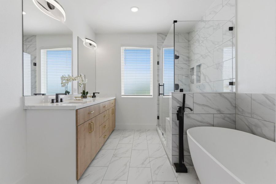 Spa-like primary bathroom featuring double sinks, a soaking tub, and a separate shower for a luxurious daily experience.