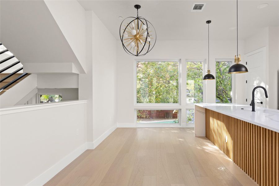 Hardwood floors and large windows define this light-filled modern kitchen and dining area.