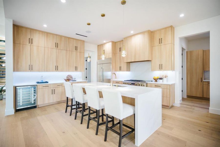 Kitchen featuring light hardwood / wood-style floors, an island with sink, light brown cabinets, and wine cooler