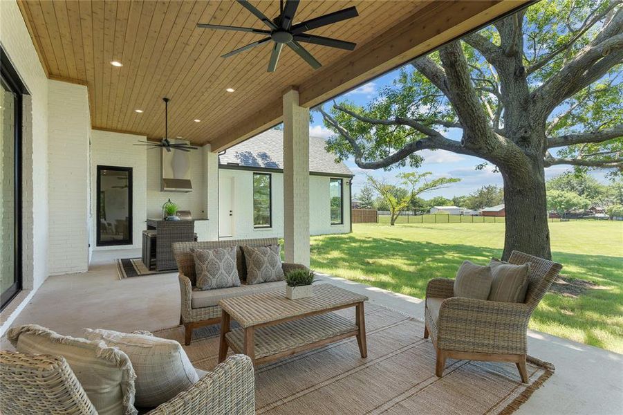 Backyard covered patio features a living area and outdoor kitchen.