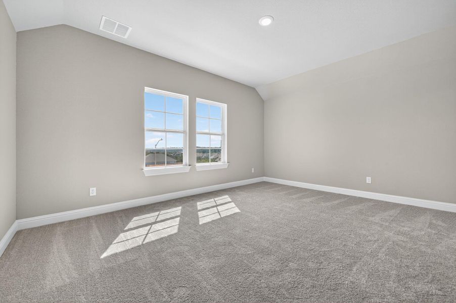 Carpeted empty room with vaulted ceiling and baseboards