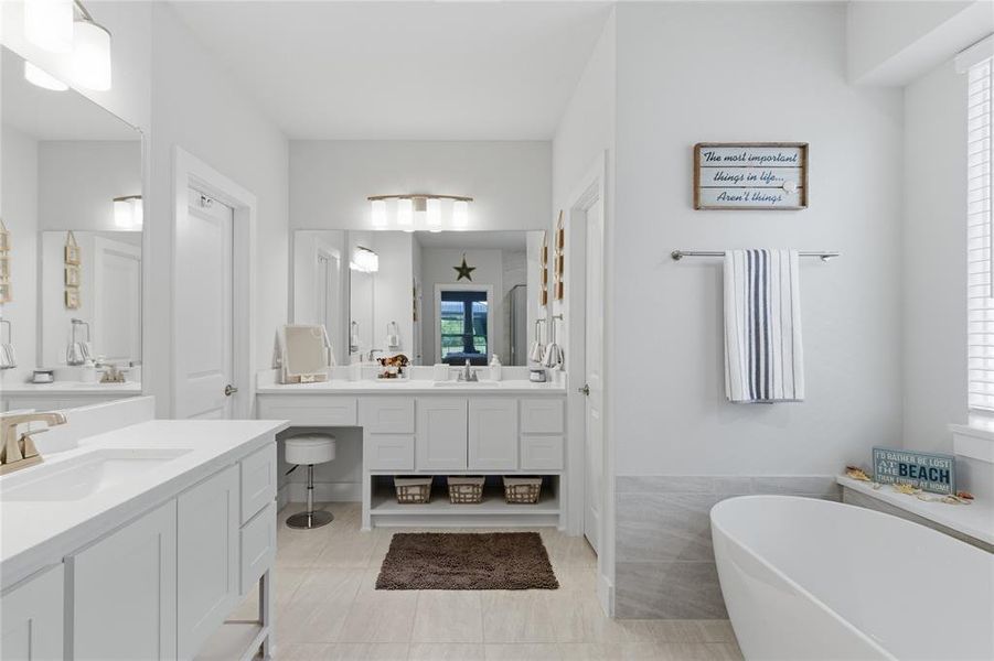 Primary bathroom featuring a freestanding soaking tub, dual vanity with undermount sinks, and a dedicated vanity seating area