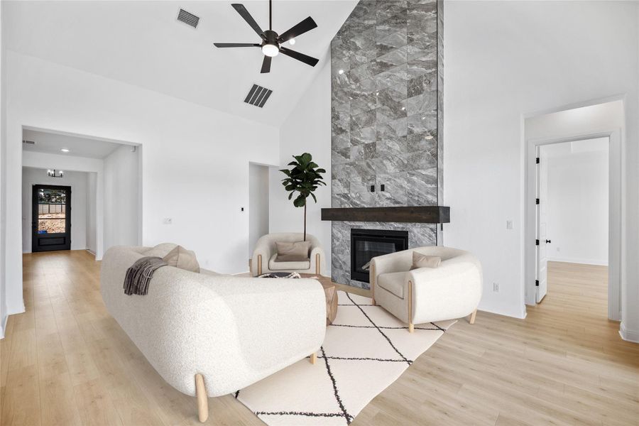 *Virtually Staged Living area featuring a premium fireplace, light wood-type flooring, ceiling fan, and vaulted ceiling