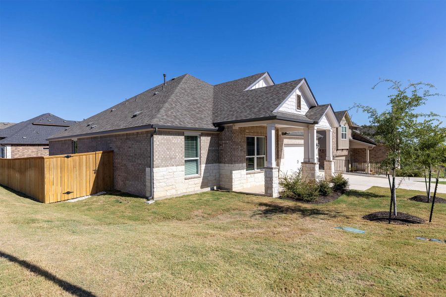 View of front of house featuring a shingled roof, brick siding, covered porch, and stone siding