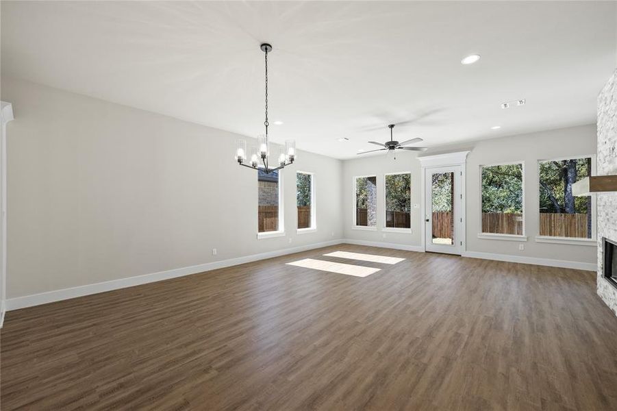 Unfurnished living room with a ceiling fan, dark wood-style floors, healthy amount of natural light, and hanging lights